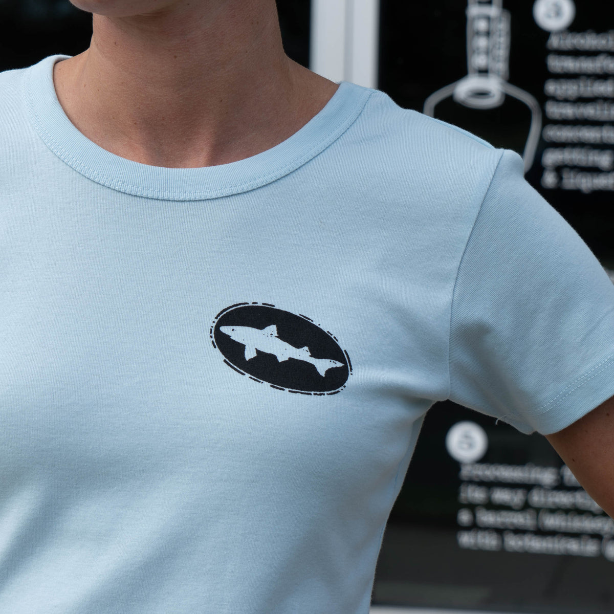 Light blue W Light Blue Hull and Helm Baby Tee Shirt featuring an oval graphic on the chest with a silhouette of a fish.