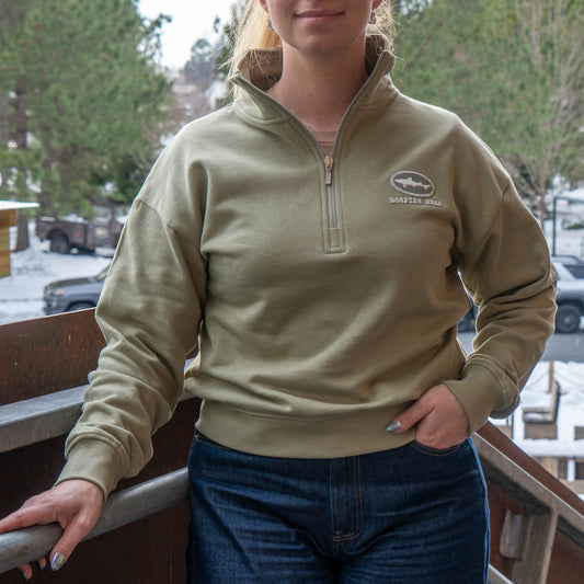 Woman wearing a Mineral Quarter Zip pullover with a Dogfish Head logo designed in Mineral Green on the front left chest