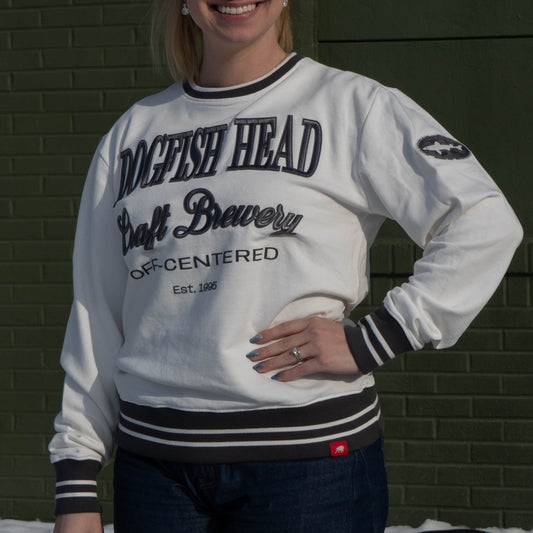 White crewneck sweater with Black and thin white striped cuffs, hemline, and neckband. Crew reads "Dogfish Head, Craft Brewery, OFF-CENTERED, Est. 1995" and has a black dogfish logo on the right bicep.