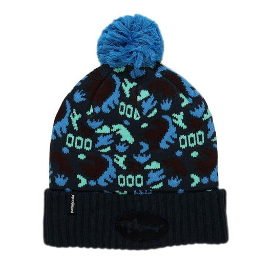 The Patagonia Black and Blue Pom Beanie features a blue pom-pom, patterned blue, teal, and black shapes, a folded ribbed brim, a black patch, and is made from recycled polyester for warmth and sustainability.