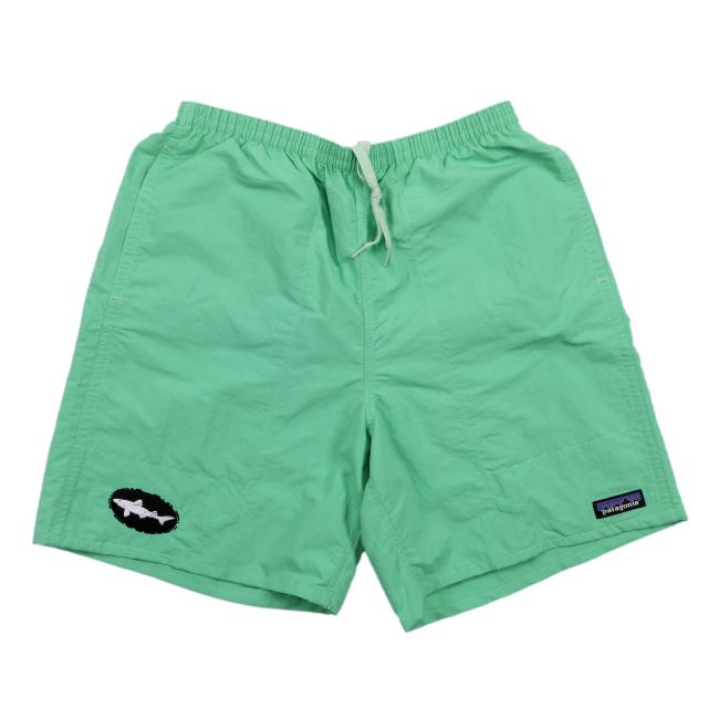 The Patagonia Green Baggies Long Shorts by Patagonia, in light green, feature quick-drying fabric, an elastic waistband with a white drawstring, and two logo patches near each leg hem. They're displayed flat on a white background.