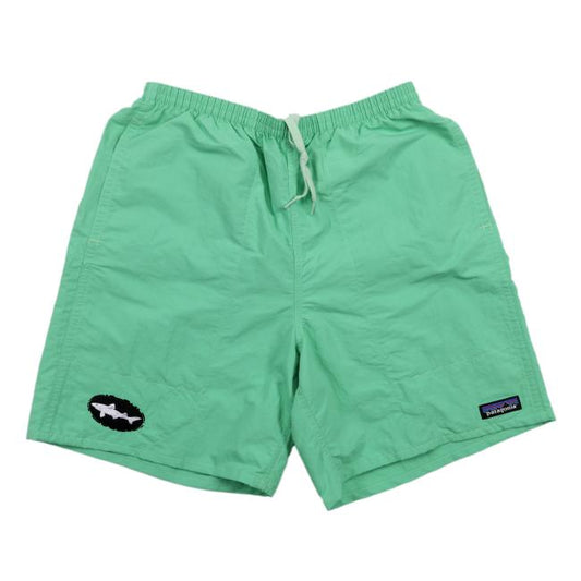 The Patagonia Green Baggies Long Shorts by Patagonia, in light green, feature quick-drying fabric, an elastic waistband with a white drawstring, and two logo patches near each leg hem. They're displayed flat on a white background.