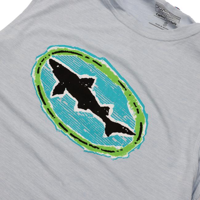 The Patagonia Light Blue Sleeveless Tank by Patagonia features a graphic of a black shark silhouette inside a blue oval with a rough green border on the chest area. Made with recycled polyester.