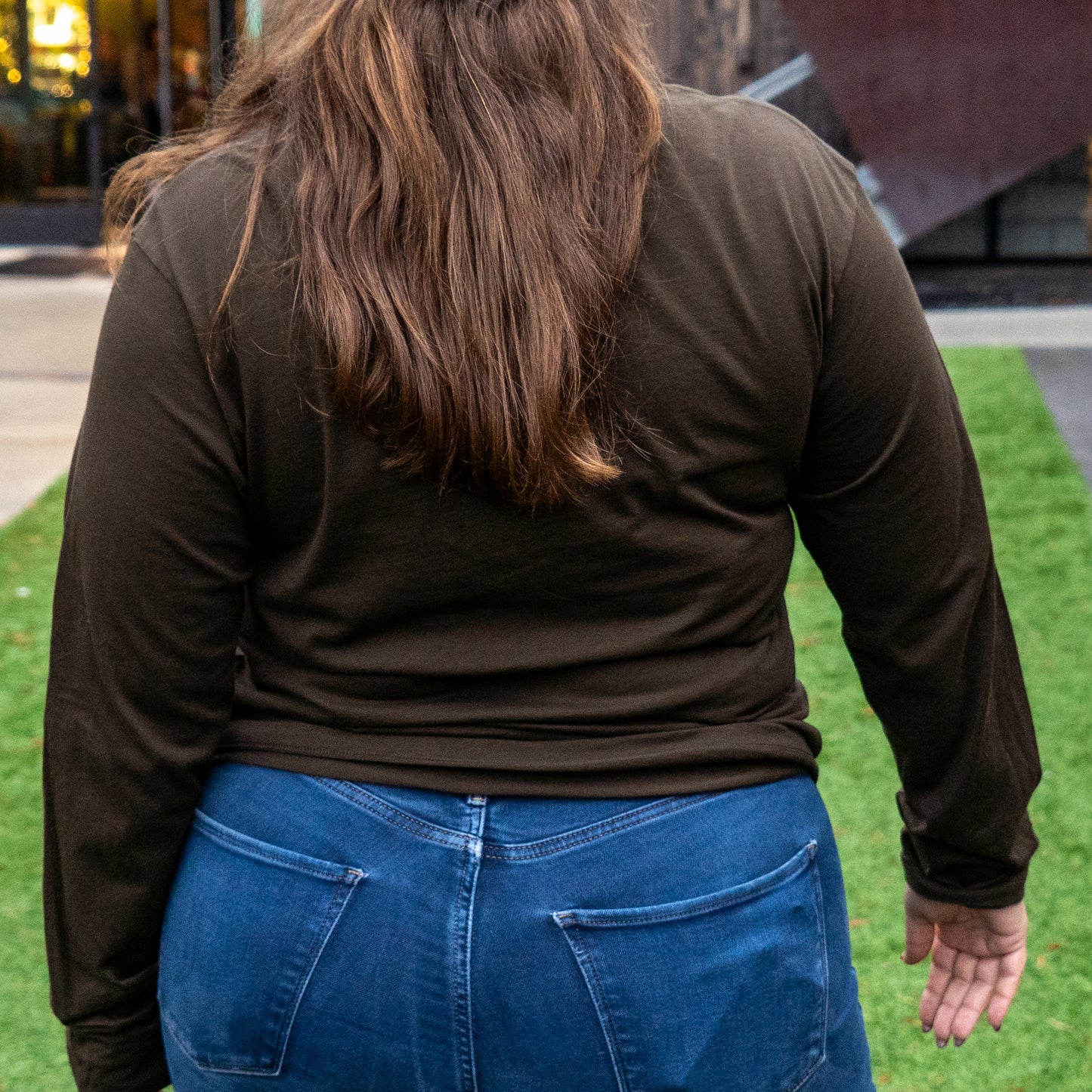 A person wearing the Patagonia M Brown Long Sleeve Henley stands on grass outdoors with their back to the camera.