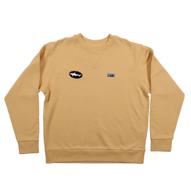 The Patagonia Tan Crewneck Sweatshirt by Patagonia is an organic cotton crewneck in light yellow with small black and white patches on the left chest and a tiny blue and gray patch on the right chest, shown on a white background.