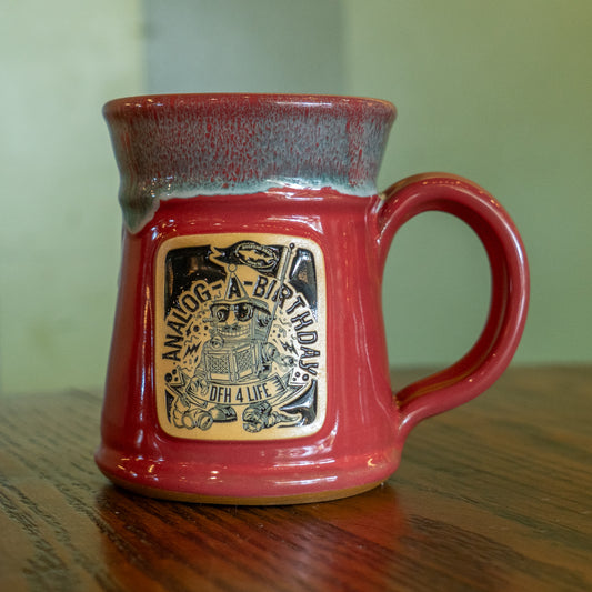 A pink Analog Splitrock ceramic mug by Deneen Pottery with a wide base, handle, and decorative plaque reading “Analog-A-Birthday, OGH 4 Life,” plus a robot holding a record player—perfect for showing off true brewery pride.