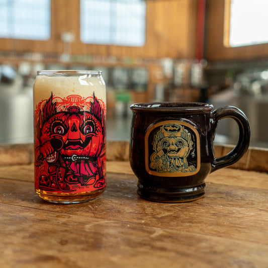 Image of Punkin can glass and mug next to each other. Can glass features red punkin artwork and mug features the same in brown and black.