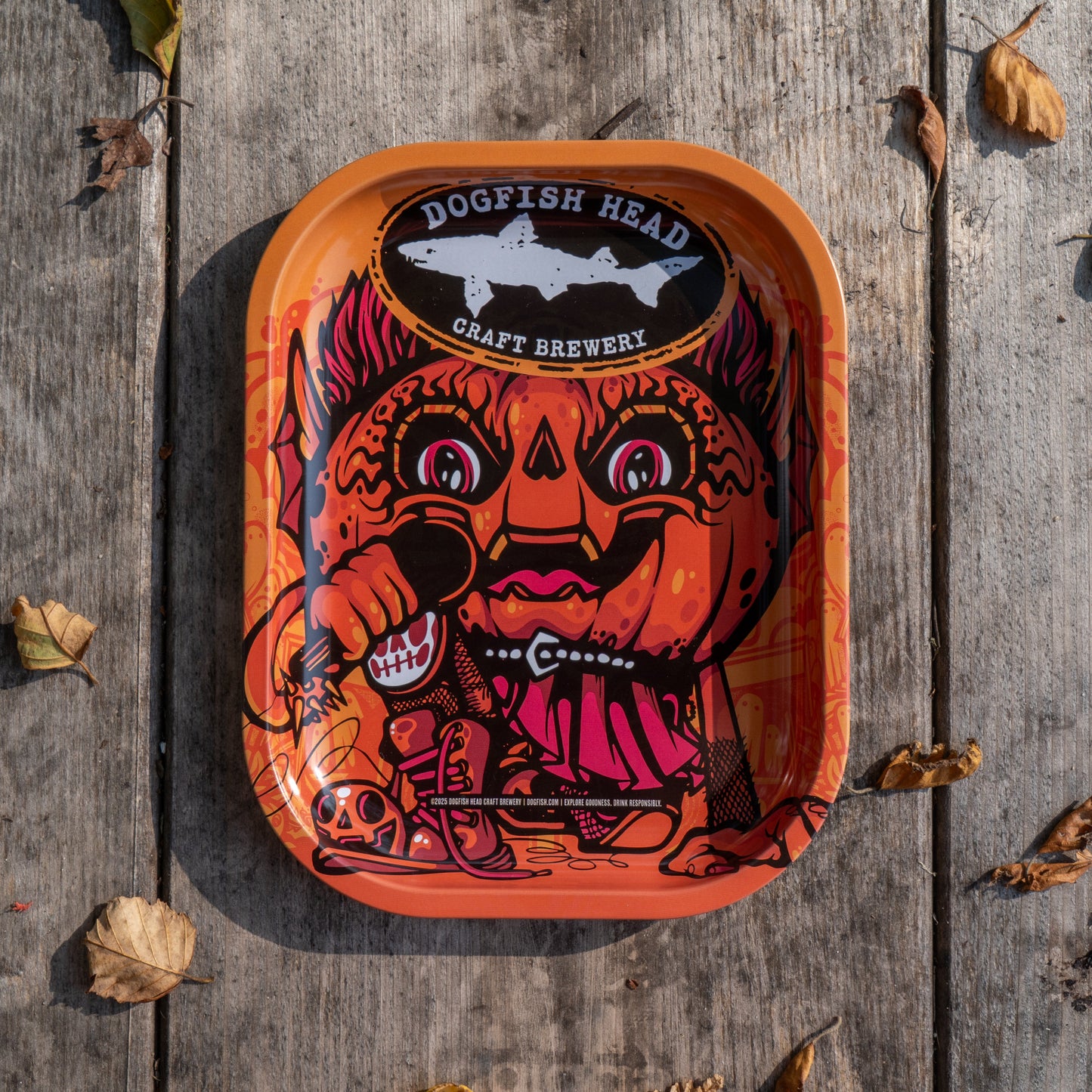 The Punkin Metal Trinket Tray from Rollyourownpapers.com features a vibrant, cartoon pumpkin-head character holding utensils on a rustic autumn background—perfect for seasonal decor.