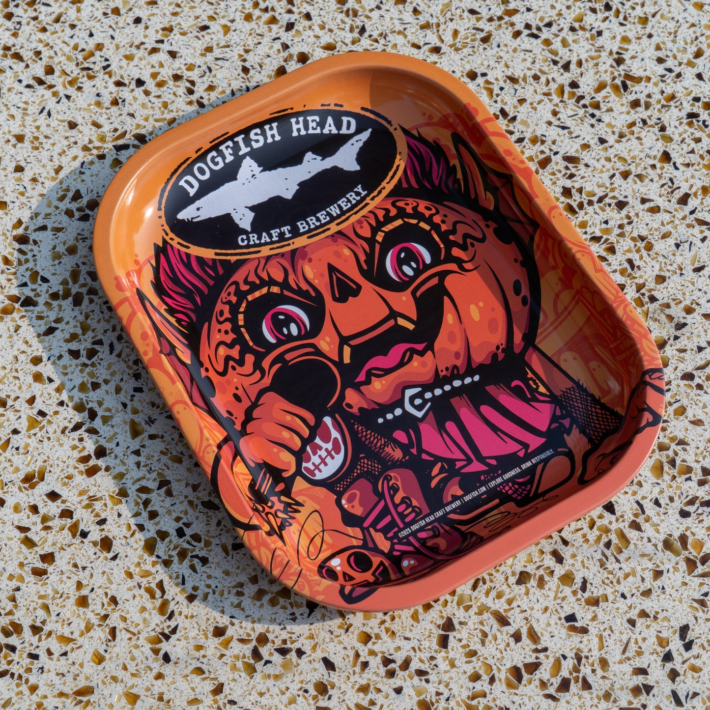 The Punkin Metal Trinket Tray by Rollyourownpapers.com features a cartoon pumpkin-headed character with bold designs, making it a quirky, colorful choice for seasonal decor on any speckled countertop.