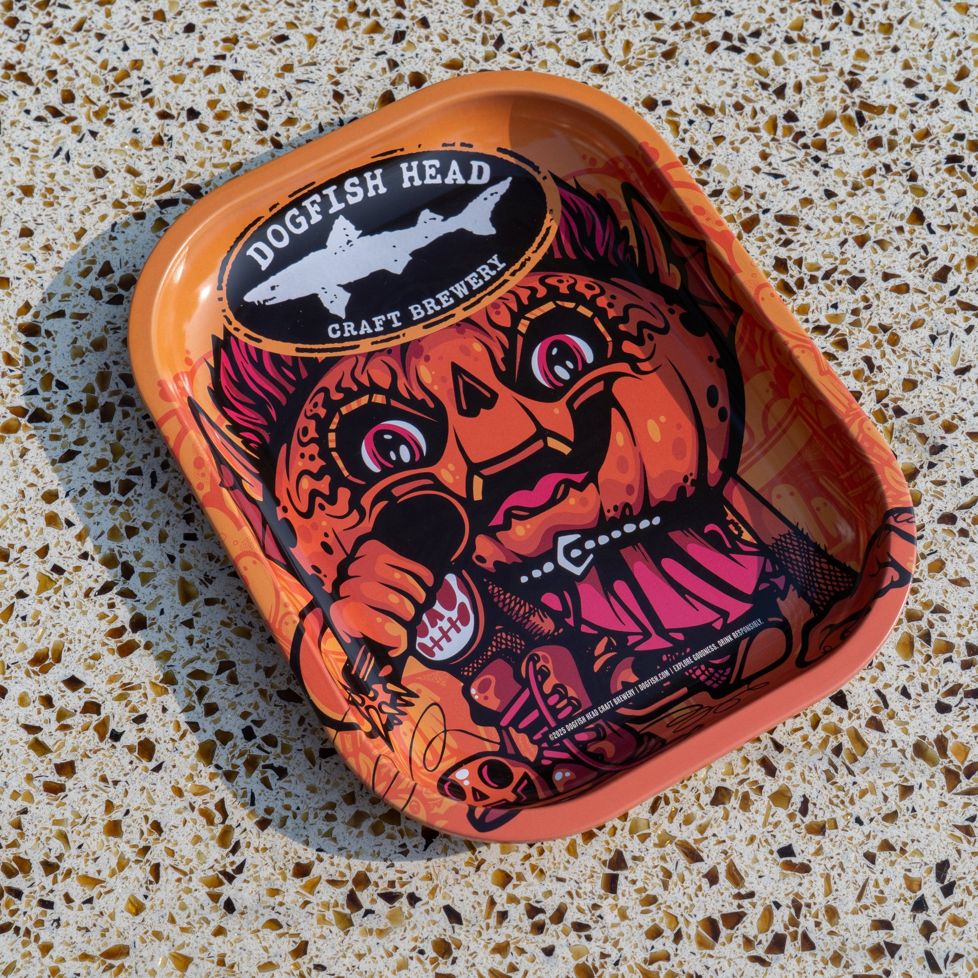 The Punkin Metal Trinket Tray by Rollyourownpapers.com features a cartoon pumpkin-headed character with bold designs, making it a quirky, colorful choice for seasonal decor on any speckled countertop.