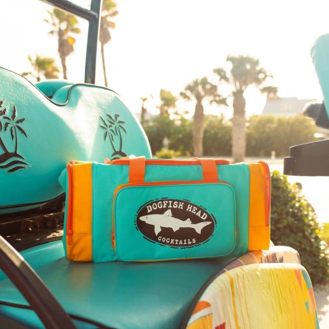 Blue cooler duffle that are orange on the sides. The center pocket on the front features a black Dogfish Head shark and shield logo.