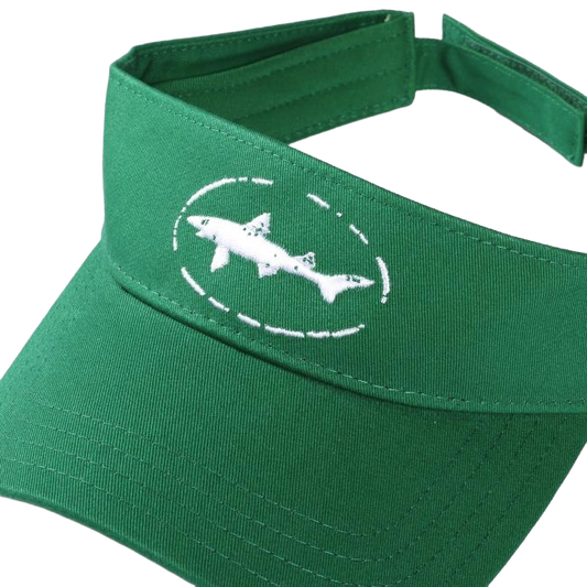 The Shark and Shield Visor by PUKKA features a green design with a white embroidered shark in a dotted oval on the front and an adjustable Velcro closure for a perfect fit.