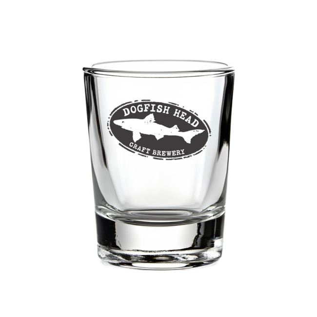 A clear 2.5 oz Shot Glass from Grandstand Glassware & Apparel, featuring a black and white fish silhouette logo on the front. Ideal for spirits, this shot glass is shown against a plain white background.