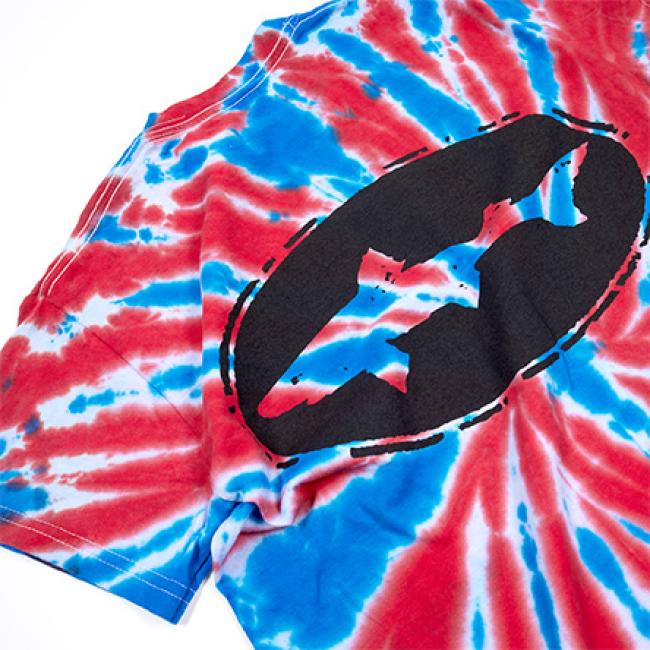 The GO WEST T-SHIRT COMPANY Tie Dye Logo Short Sleeve Tee features a bold black Batman logo on the chest, showcased on a vibrant red, white, and blue spiral tie dye pattern. Unisex design with short sleeves, displayed flat to highlight its style.