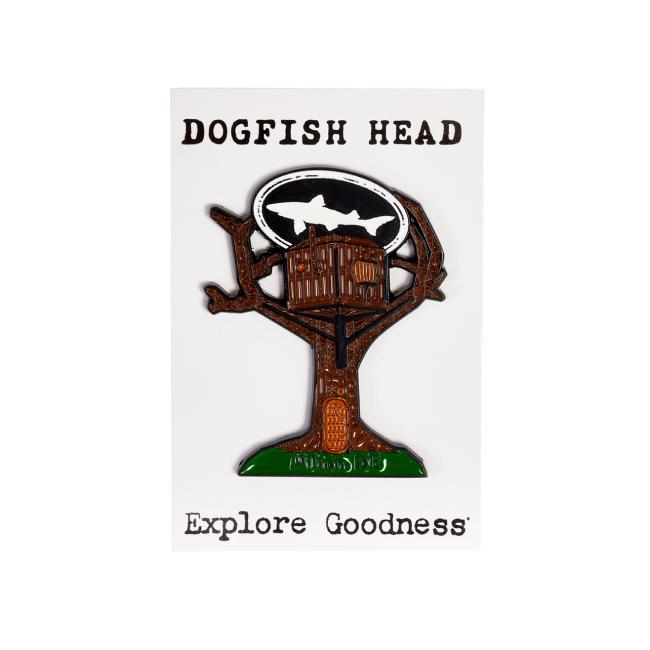 The Treehouse Pin by Arrasmith Promotions LLC features a treehouse with a shark silhouette in an oval, displayed on a white card labeled "DOGFISH HEAD" at the top and "Explore Goodness" at the bottom.