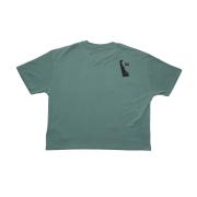 The GO WEST T-SHIRT COMPANY W Green Delaware Logo Short Sleeve Tee is an oversized, muted green organic cotton shirt with a small black logo near the right shoulder, shown from the back.