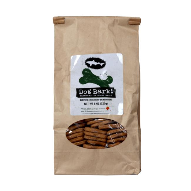 A brown paper bag labeled Waggies Dog Treats from Waggies by Maggie & Friends Inc, with a clear window showing round brown treats. The label features a green bone graphic and a black dog silhouette.