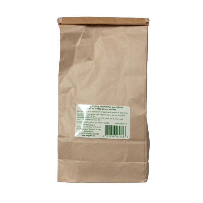 A plain brown paper bag of Waggies Dog Treats by Waggies by Maggie & Friends Inc, featuring a rectangular white and green label with text and a barcode, stands upright against a white background.