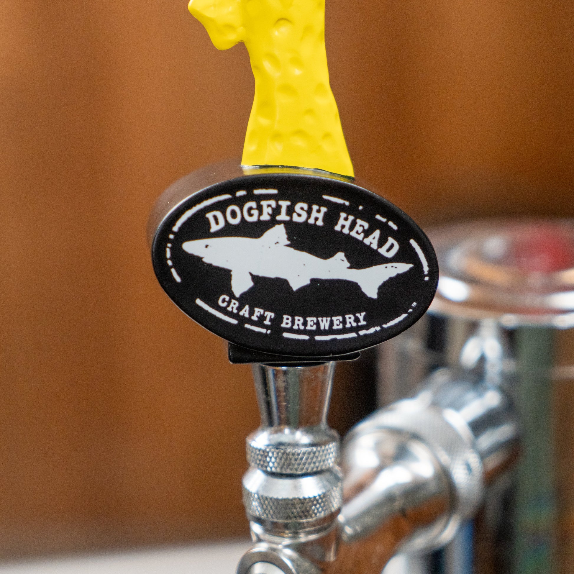 A close-up of a Merchtank Tap Handle - Shorty with a neon yellow top, attached to a shiny metal tap—perfect for serving your favorite brews.