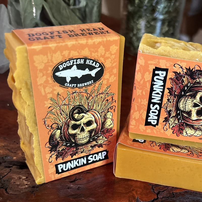 Two orange bars of Punkin Soap by DFH Craft Brewery rest on a wooden surface. The packaging displays a skull adorned with a pumpkin, leaves, and autumn-inspired designs—perfect for bringing a distinctive flair to your daily routine.