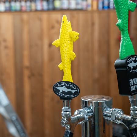 Yellow shark handle shown on tap next to green shark tap handle. Black base of handle features Dogfish Head shark and shield logo.