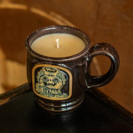 Image of black mug filled with candle. Mug has brown and black Punkin artwork on the front of it.
