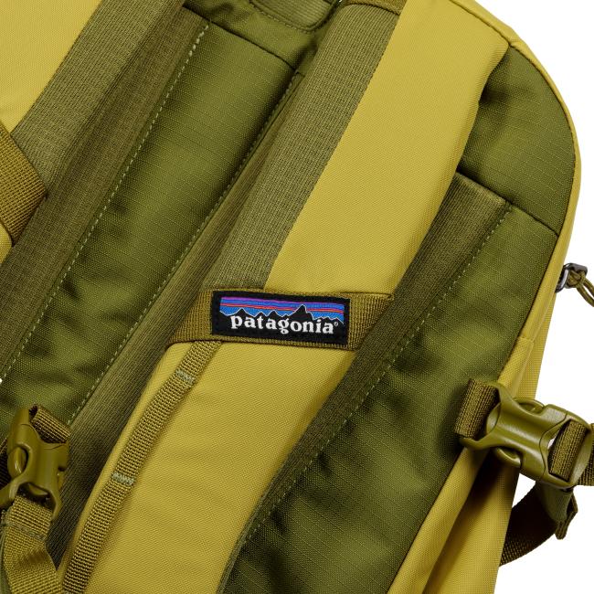 Detail shot of the back strap area highlighting the woven Patagonia logo tag stitched onto mustard and olive-colored padded straps.