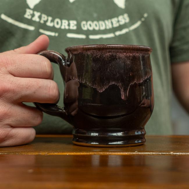 Back of black glazed mug with pink glaze on top.