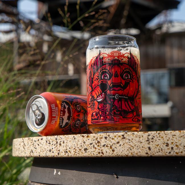 Front of can glass features orange red Punkin artwork, with the Punkin ale can in the background.