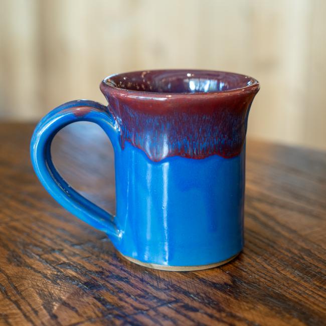 Back view of the mug is solid blue with the red drip glaze up top.