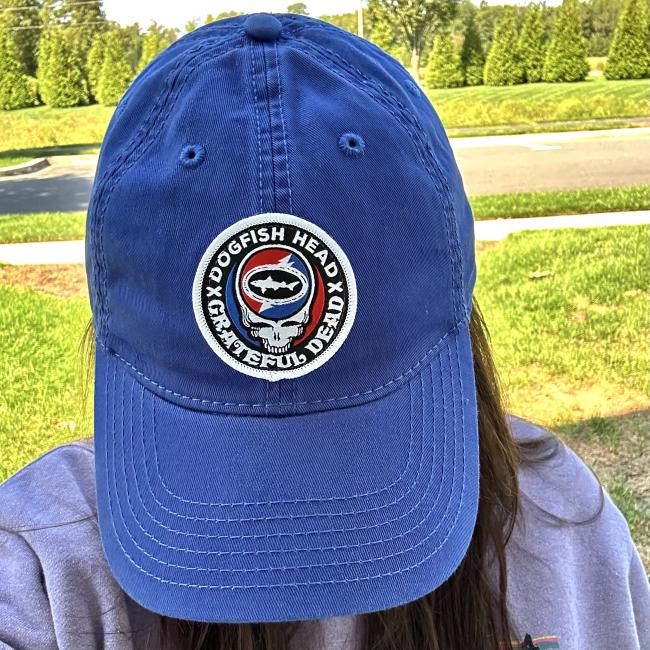 Front view of royal blue hat shown worn. Hat features Dogfish Head x Grateful Dead collaboration logo emblem centered to front of the hat.