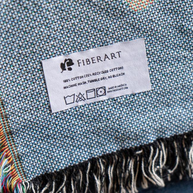 Close-up of tag on blanket, featuring brand, fabric, and wash instructions.