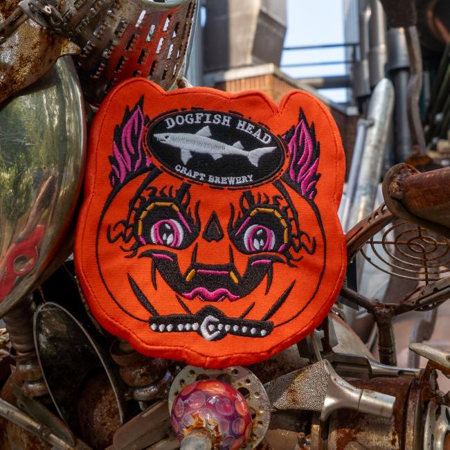Orange punkin dog toy is in the shape of the artwork with the Dogfish Head shark and shield logo up top.