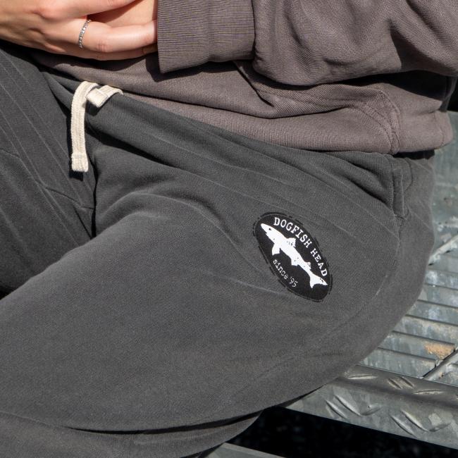 Close-up of the top left of pant which features the black and white Dogfish Head shark and shield logo.