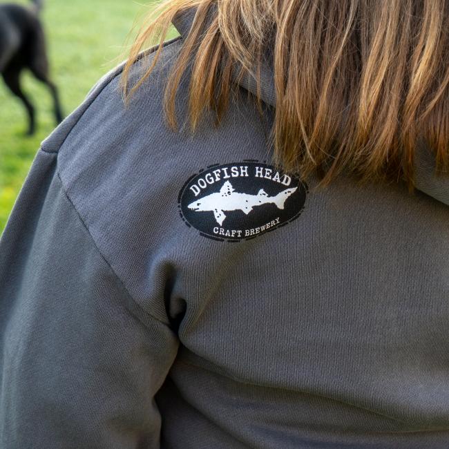 Close-up of black and white shark and shield Dogfish Head logo located on top left of back of hoodie.