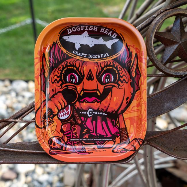 Orange tray covered in Punkin artwork, with Dogfish Head shark and shield logo on top.