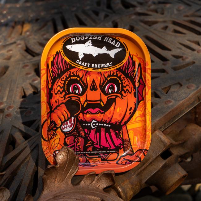Orange tray covered in Punkin artwork, with Dogfish Head shark and shield logo on top.