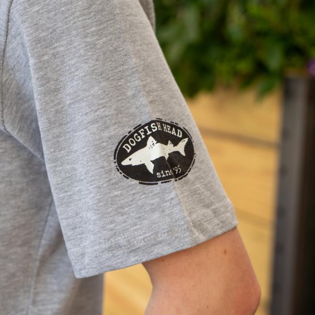 Close-up of left sleeve of tee features black and white Dogfish Head shark and shield logo.