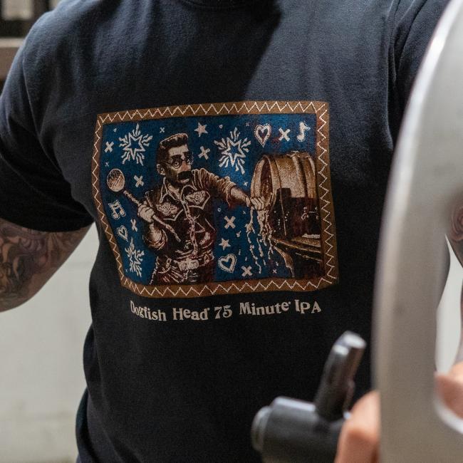 Shown by a person wearing, close-up of front view of the shirt features Jon Langford's retro label artwork on a blue background, along with writing