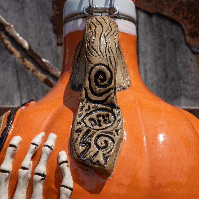 Close-up of the growler handle which is brown made to look like a tree branch. Skeleton hand is featured on the bottom of the growler.