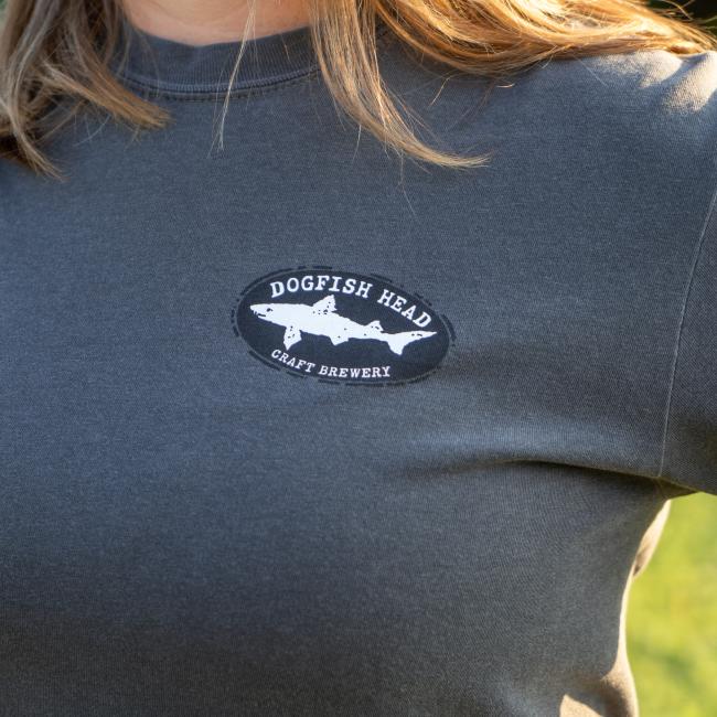 Close-up of Dogfish Head shark and shield logo on left side of chest featured on the front of tee.